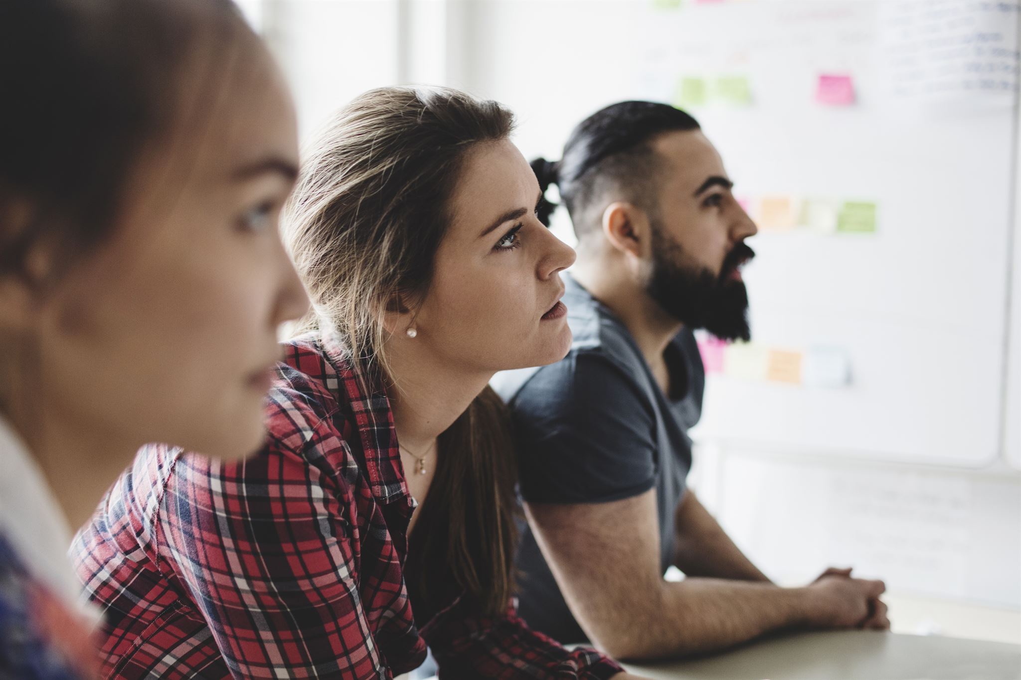 Close-up-of-three-casual-professionals-watching-presentation-in-creative-office